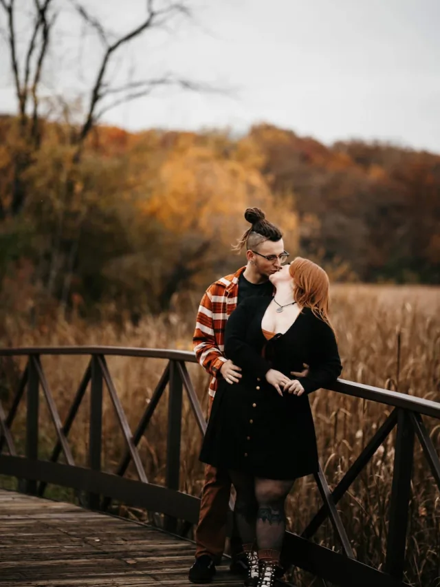 Autumn and Grayson embracing on a bridge surrounded by fall color