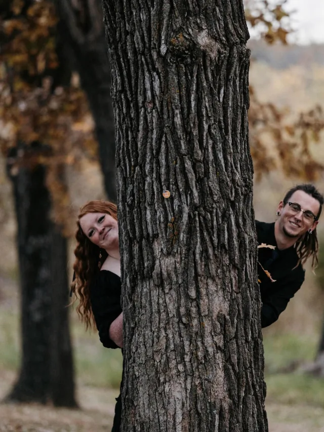 Autumn and Grayson smiling from opposite sides of a tree